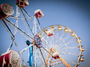 Ferris wheel and carnival rides against a blue sky at the Washington State Fairgrounds